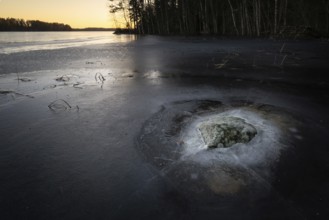 Mossy rock surrounded by ice in a frozen lake, Finland