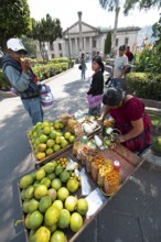 Parque Centroamérica or Parque Central, a Mayan woman in traditional clothes peels oranges,