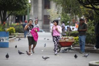 Guatemalan woman with toddlers in modern clothes stroll across Parque Centroamérica or Parque