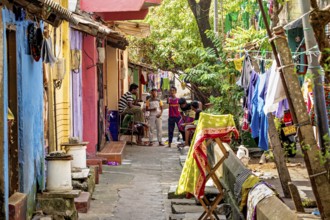 Colourful residential buildings in a narrow street with hanging laundry and people playing