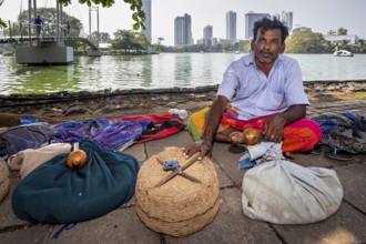 Man on the riverbank with filled baskets against an urban backdrop, relaxed and traditional