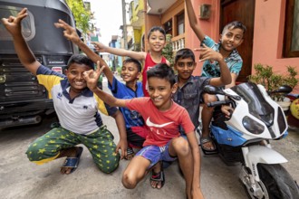Children pose with a toy motorcycle on the street and are obviously having fun