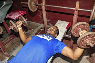 Man lifting weights on a bench in a rustic gym