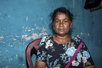 Portrait of a woman in front of a blue, peeling wall in an interior