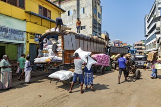 Bustling street scene in India, workers loading a truck in a market district, loading a truck in
