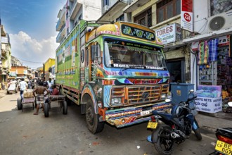Colourful truck on a busy Indian street with shops and people in sunny weather, The colorful trucks