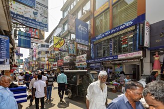 Populated street with shops and eye-catching advertising posters under clear skies, the hustle and