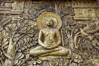 Relief depiction of Buddha in meditation surrounded by plants and architectural details, statues of
