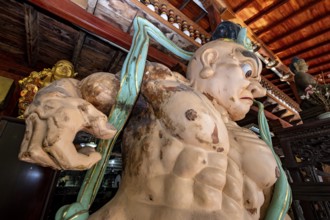 Large wooden sculpture with Buddhist theme in traditional setting, statues of gods in Colombo