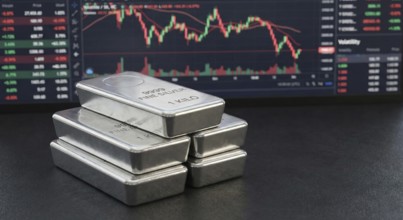 Stacked 99.99% fine silver bars are displayed in front of a digital financial chart, symbolising