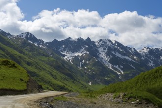 Snow-capped mountains and a road under a cloudy sky, mountains near Ushguli, Upper Svaneti,