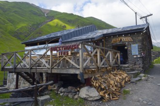 Guesthouse with wooden veranda in a mountain landscape under a cloudy sky, Cafe Svaneti, Ushguli,