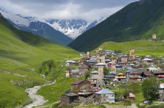 Mountain village with numerous towers and a river, surrounded by green hills, defensive towers,