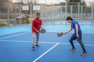 Two men intensely competing in pickleball on a vibrant blue outdoor court, focused and athletic as