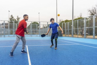 Two young menone african american, one caucasiancompete in an energetic outdoor pickleball rally,