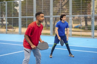 Two young diverse men holding paddles and concentrating on the game, actively participating in a