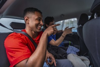 Young male pickleball players sharing a ride in a car, smiling and pointing while traveling