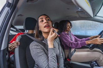 Women friends traveling together in a car, with a passenger applying lipstick using a makeup pencil