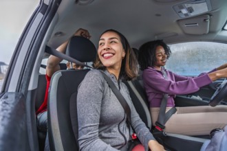 Diverse friends in athletic wear smiling in a car, seatbelts on and ready for a fun pickleball