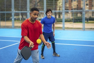 Young diverse men playing pickleball, engaging in active recreation and enjoying the outdoor sports