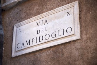 Stone road sign with the inscription 'Via del Campidoglio' on an ancient wall, Capitol Square,