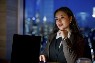 Young businesswoman with elegant hairstyle working late hours, researching or analyzing data on her