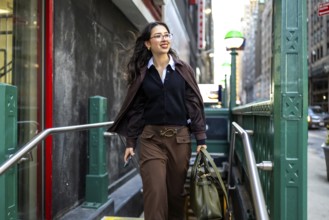 Young businesswoman with glasses and a professional bag emerging from a subway station entrance,