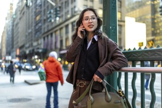 Young businesswoman in manhattan walking and talking on a smartphone, dressed smart casual,