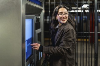 Young businesswoman with glasses and dark coat smiling, looking over her shoulder while interacting