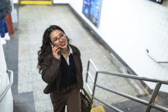 Young businesswoman with glasses and a professional outfit talking on a mobile phone while