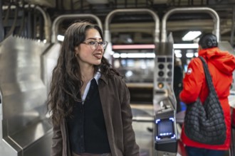 Young businesswoman enters a manhattan subway station, scanning her card at the turnstile during a