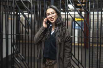 Young businesswoman standing in a new york city subway station, smiling while having a business