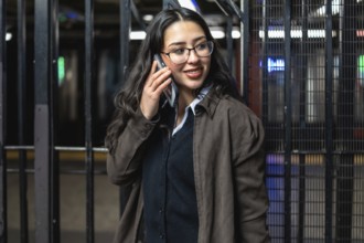 Young professional businesswoman smiling, talking on a mobile phone, and standing on a new york