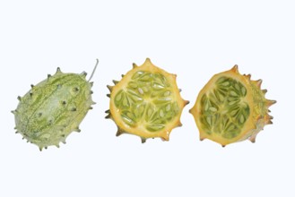 Horned cucumber, kiwano or horned melon (Cucumis metuliferus), whole and sliced fruit on a white