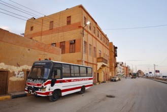 Bus parked on a street and houses, Esna, Egypt