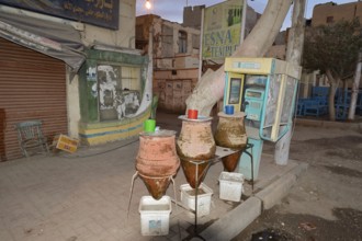 Telephone box and clay carafes with drinking water, Esna, Egypt