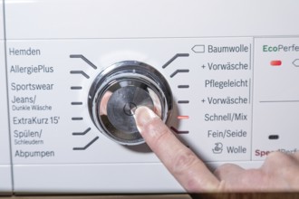Woman turning the dial of a washer to start cleaning. Germany