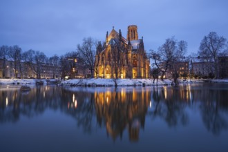 March 18, 2018, winter dusk with snow, illuminated lake and Gothic church Johanneskirche, calm