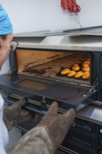A baker takes freshly baked rolls out of a hot oven, bake rolls, Haselstaller Hof, Gechingen,