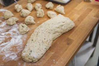 A large lump of dough together with pieces of dough on a wooden table, baking rolls, Haselstaller