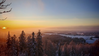 A wintry sunset over a snow-covered forest with glowing sky, Frankenwald nature park Park, Upper