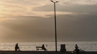 People sitting and bikers by the sea at sunset, quiet and peaceful atmosphere, waterfront, Izola,