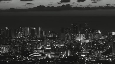 City view at night with illuminated skyscrapers and clouds in the sky in black and white, Batumi,