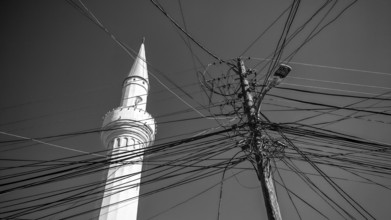 A minaret and numerous power lines against a monochrome sky, Prizren, Kosovo
