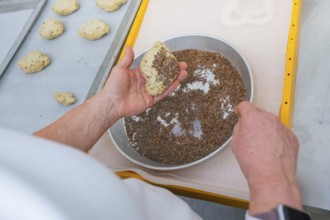 A baker sprinkles a dough with linseed on a baking tray, bake rolls, Haselstaller Hof, Gechingen,