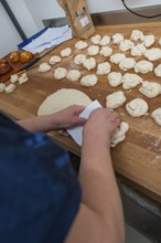 A baker kneads dough on a wooden work surface in the bakery, baking rolls, Haselstaller Hof,