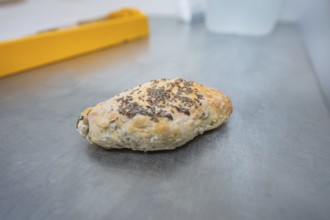 A roll with chia seeds is lying on a metal work surface in the bakery, bake rolls, Haselstaller