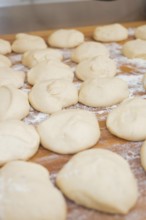 Unbaked dough balls with flour on wooden table to prepare for baking, baking rolls, Haselstaller