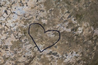 Close-up of painted black heart outline symbol on tanned nuanced rock surface, Quebec, Canada