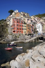 Colourful houses under blue sky, view of the fishing village of Riomaggiore, boats in the harbour,